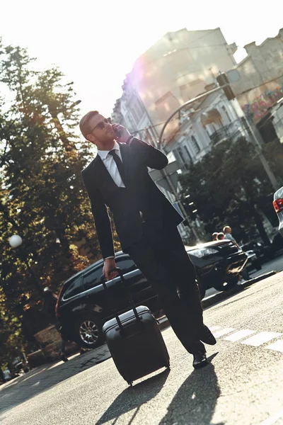 Бизнесмен Костюме Прогуливается Городской Улице Багажом Разговаривает Мобильному Телефону — стоковое фото