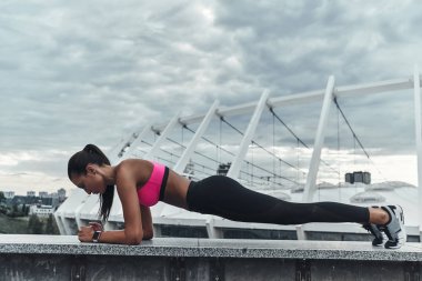 sportif kadın tutmak plank pozisyon ve çatı yapı üzerinde açık havada egzersiz 