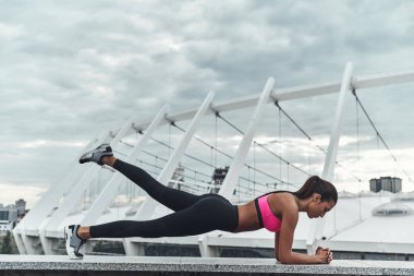 sportif kadın tutmak plank pozisyon ve çatı yapı üzerinde açık havada egzersiz 