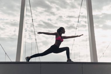 sportif kadın açık havada bulutlu gökyüzü karşı modern binanın çatı üzerinde uzanan 