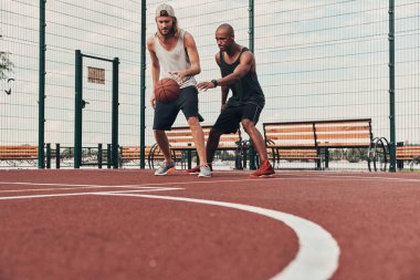 İki genç erkek basketbol oynarken 