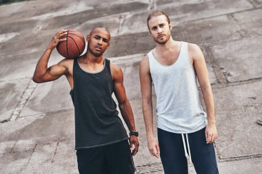 Genç yakışıklı erkekler basketbol topu ile ayakta açık havada süre kameraya bakarak giyim spor