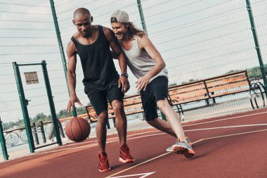 İki genç erkek basketbol oynarken 