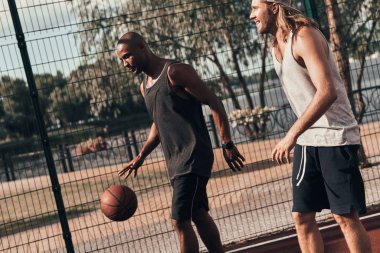 İki genç erkek basketbol oynarken 