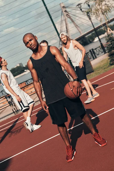 Kamera arka plan üzerinde arkadaşlarıyla basketbol sahası üzerinde dururken bakarak giyim spor Afrika delikanlı 