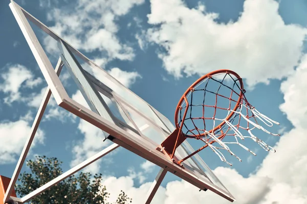 basketball hoop with sky on background, basketball net against cloudy sky