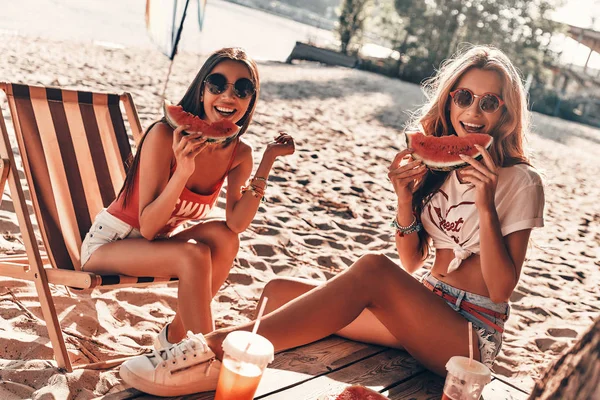 Dwie Atrakcyjne Młode Kobiety Uśmiechając Się Jedzenie Arbuza Siedząc Plaży — Zdjęcie stockowe