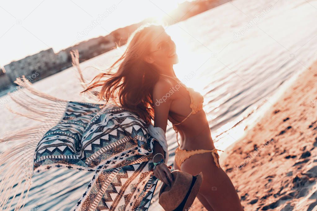 beautiful woman laughing on beach and wearing yellow bikini and pareo clothing