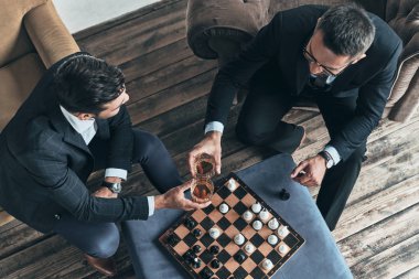 satranç oynamayı ve viski bardağı ile tungur tam elbiseli adamlar üstten görünüm