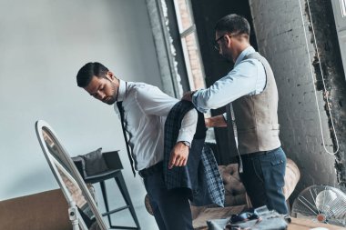 Butik atölyede dururken ceket giyinmiş için moda tasarımcısı yardımcı istemci