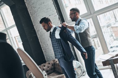 Atölyede dururken ceket giyinmiş için moda tasarımcısı yardımcı istemci