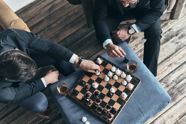 top view of men in full suits playing chess while sitting indoors