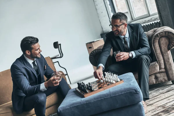 Homens Bonitos Trajes Completos Jogando Xadrez Sorrindo Enquanto Sentados Dentro — Fotografia de Stock