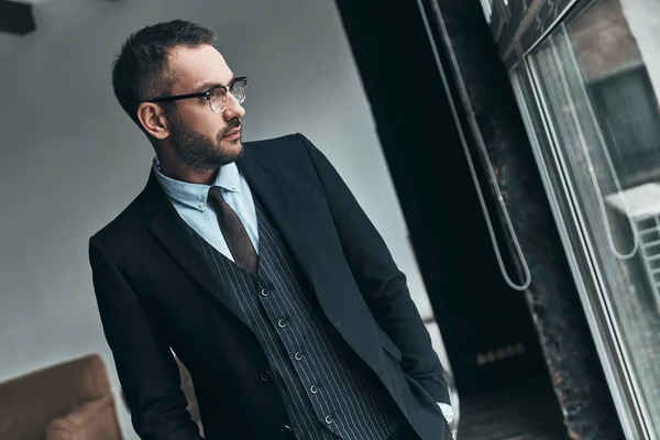 Omtänksamma Mannen Full Kostym Tittar Bort Genom Fönstret Medan Stående — Stockfoto