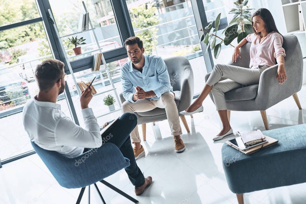 young married couple talking while sitting on therapy session with psychologist               