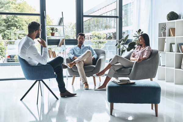 young married couple talking while sitting on therapy session with psychologist