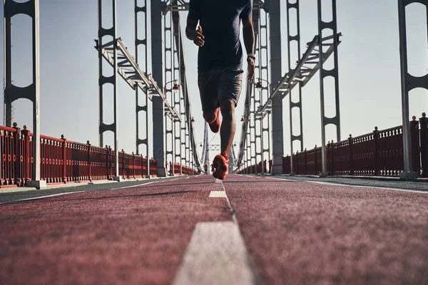 man jogging on bridge outdoors, low angle view, cropped image