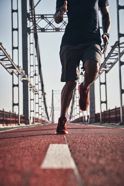 man jogging on bridge outdoors, low angle view, cropped image