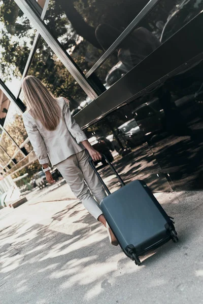 エレガントな女性の屋外ストリート道路を歩きながら荷物を引っ張っての背面図 — ストック写真