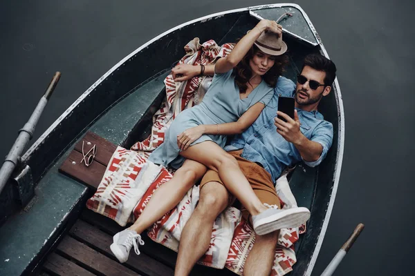 top view of beautiful young couple taking selfie with smart phone while lying in boat