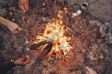 Açık havada kamp sırasında şenlik ateşi üzerinde marshmallows kavurma insanların en iyi görünümü kadar kapatın