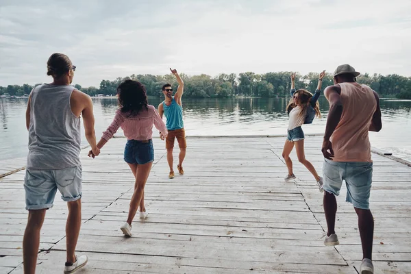 Gruppen Glada Människor Fritidskläder Som Körs Träbrygga Vid Sjön — Stockfoto