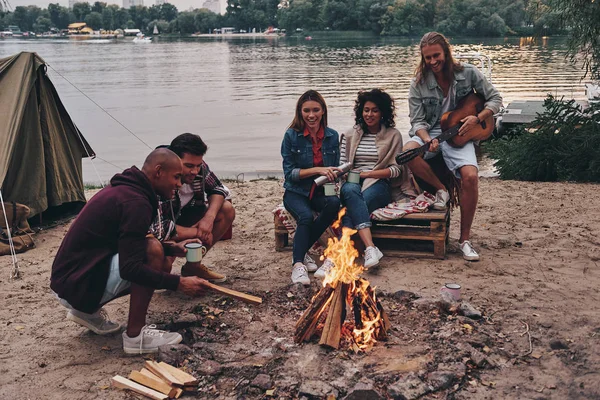 Gençlerin Rahat Kıyafet Adam Gitar Çalmak Batımında Göl Kenarında Kamp — Stok fotoğraf