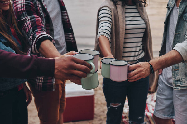 cropped image of people hands holding travel cups outdoors at picnic toasting 