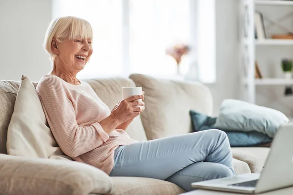 Laughing Senior Caucasian Woman Sitting Sofa Home Holding Tea Cup — Stock Photo, Image