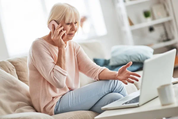 Serious Working Senior Caucasian Woman Talking Mobile Phone While Sitting — Stock Photo, Image