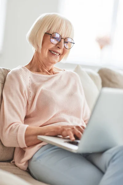 Sorrindo Mulher Caucasiana Envelhecida Sentada Sofá Casa Segurando Laptop Nos — Fotografia de Stock