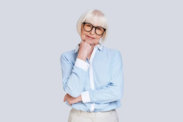 青いシャツとメガネのあごを手でスタジオの灰色の背景にポーズで笑顔の白人女性 — ストック写真