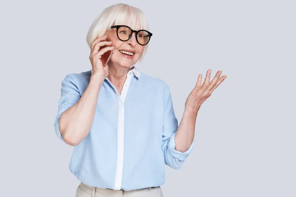 青いシャツを着て携帯電話で話している年配の白人女性 — ストック写真