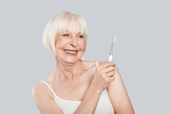 Sonriente Mujer Mayor Sosteniendo Cepillo Dientes Pie Sobre Fondo Gris — Foto de Stock