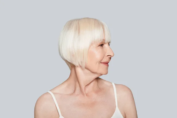 Glimlachend Senior Vrouw Zoek Weg Poseren Een Grijze Achtergrond Weg — Stockfoto