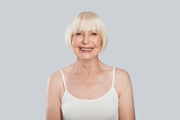 Sonriente Caucásico Pensionista Mujer Posando Gris Fondo Estudio Mirando Cámara — Foto de Stock