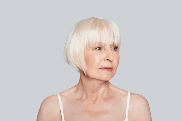 Senior Vrouw Zoek Weg Poseren Een Grijze Achtergrond — Stockfoto