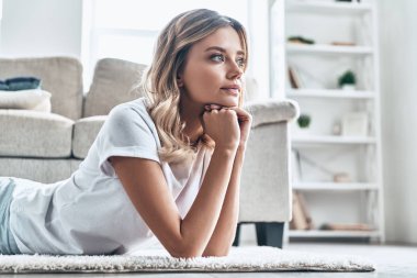 Güzel genç kadın uzağa bakarak hayal ve evde yerde yatarken  