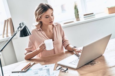 kağıtları belgeler ve dizüstü bilgisayar ile masada çalışma Kupası olan güzel kadın 