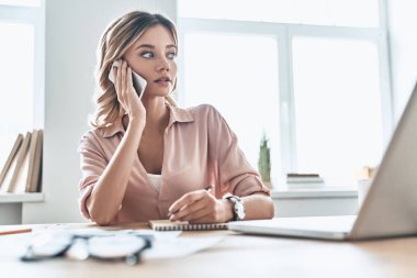 hareket eden telefon içinde modern ofis dizüstü bilgisayar ile masada konuşurken iş kadını