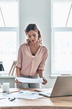 dizüstü bilgisayar ile masada duran belge bakarak düşünceli kadın 