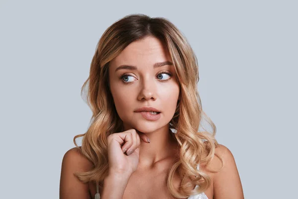 Confused Young Woman Looking Away Biting Lip While Standing Grey — Stock Photo, Image