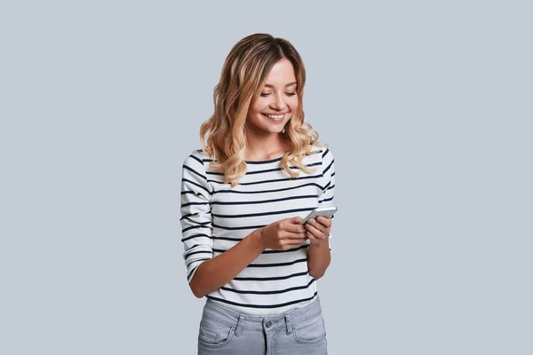 Aantrekkelijke Jonge Vrouw Lachend Met Behulp Van Slimme Telefoon Terwijl — Stockfoto