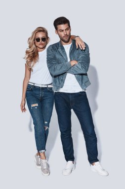 Denim giyim gri arka plan karşı dururken kucaklayan güzel genç çiftin tam uzunlukta