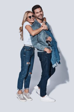 bağ ve gri arka plan karşı dururken gülümseyen giyim denim mutlu güzel genç çift
