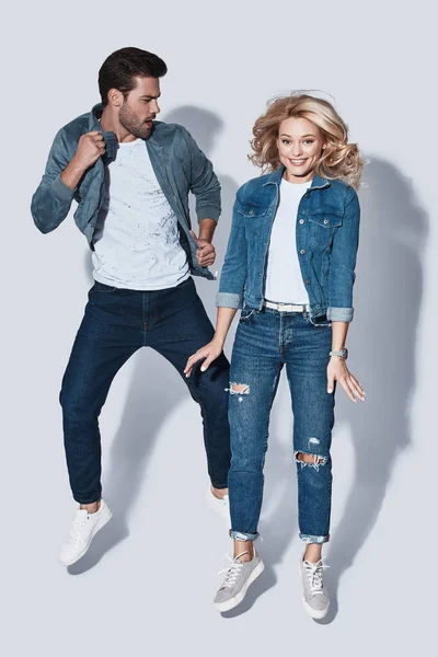 Pareja Moda Denim Desgaste Saltar Sobre Fondo Gris — Foto de Stock