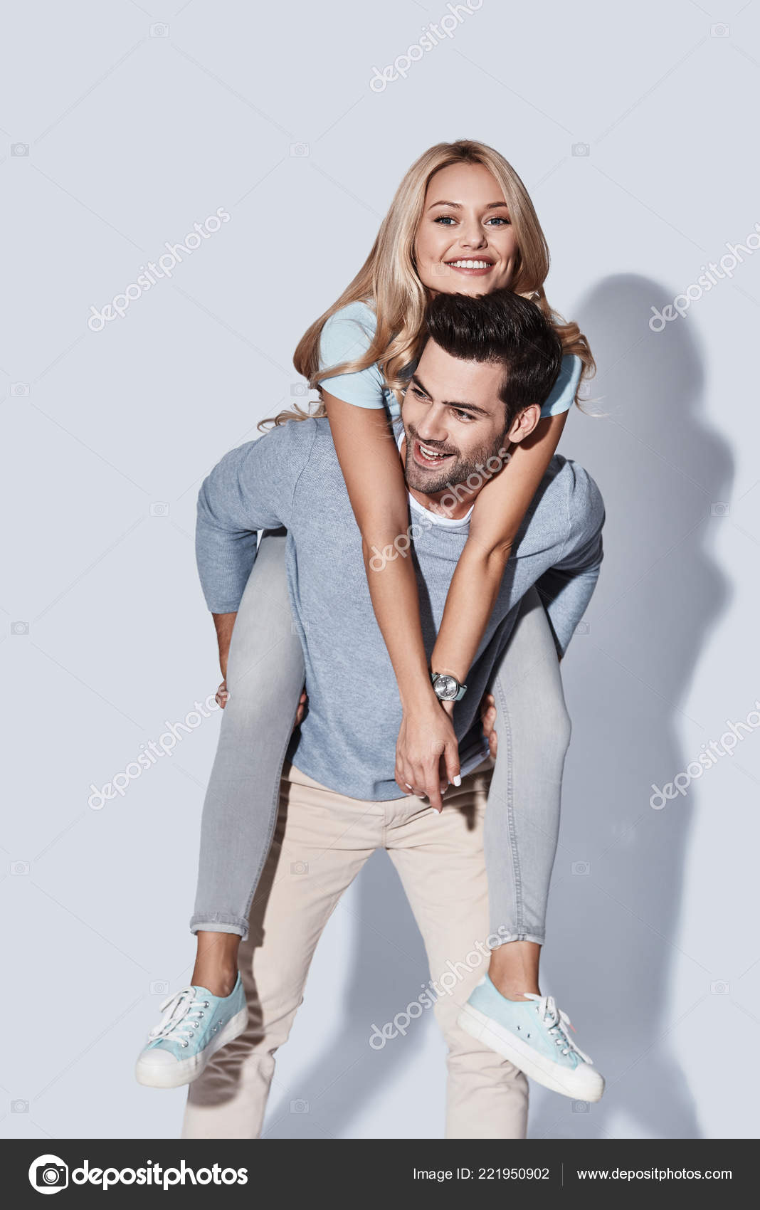 Cheerful woman holding on to boyfriends head while having piggyback ride  stock photo