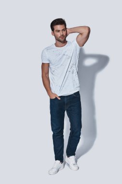 casual yakışıklı genç adam tam uzunlukta giymek uzakta cebinde el ile gri arka plan karşı duran ve saç dokunmadan arıyorsunuz 