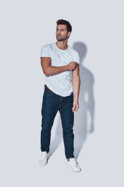  Güven yakışıklı genç adam casual giyim uzak duran gri arka planı arıyorum