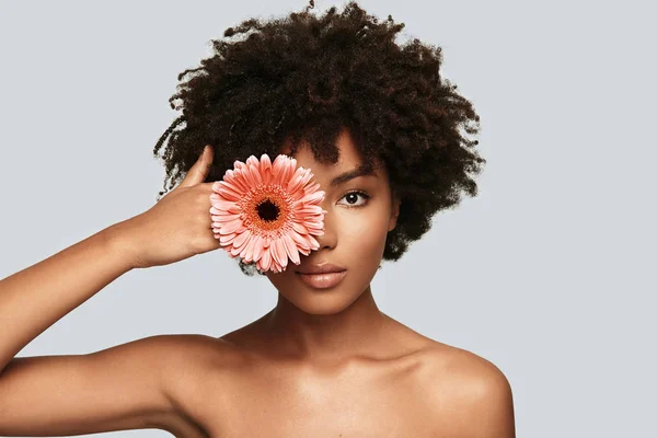 スタジオ カメラ目線と花で目をカバーの若いアフリカ女性の上半身裸の肖像画 — ストック写真